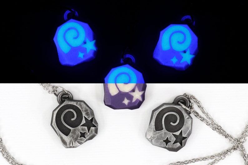 May include: Three silver necklaces with a glow-in-the-dark charm featuring a spiral and stars. The charms are in the shape of a rock.