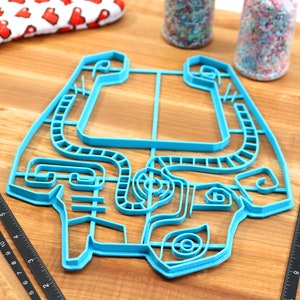 Peut inclure: Un emporte-pi&egrave;ce en plastique bleu en forme de labyrinthe. L'emporte-pi&egrave;ce est sur une surface en bois.
