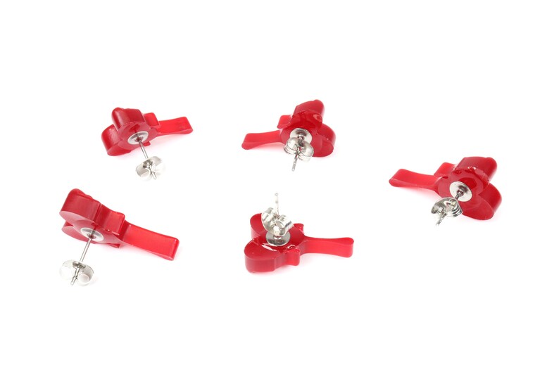 May include: Four pairs of red flower-shaped stud earrings with silver posts. The earrings are displayed on a white background.