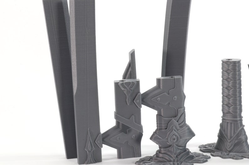 May include: Four grey 3D printed sword blades with intricate details. The blades are in various stages of completion, with some having handles and others just the blade.