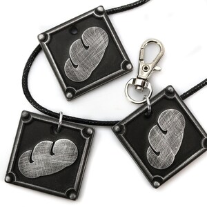 May include: Three silver-colored pendants with a black background and a cloud-like design. The pendants are attached to black cords and a silver clasp.