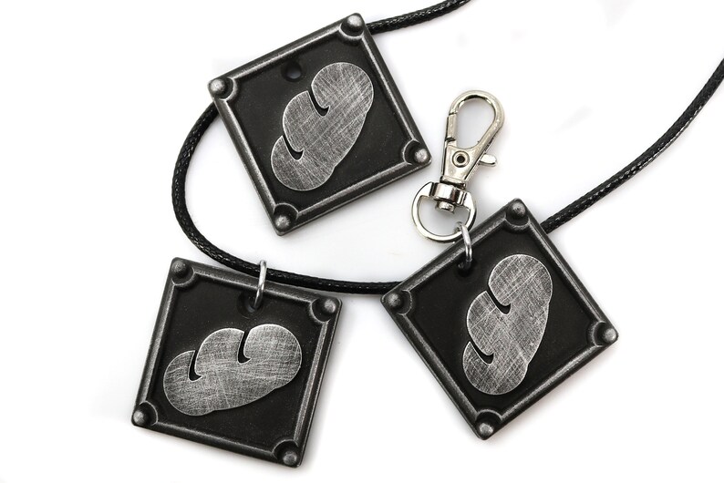 May include: Three silver-colored pendants with a black background and a cloud-like design. The pendants are attached to black cords and a silver clasp.
