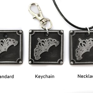 May include: Three silver-toned metal pendants with a decorative design. The pendants are shown in three different styles: standard, keychain, and necklace.