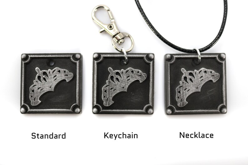May include: Three silver-toned metal pendants with a decorative design. The pendants are shown in three different styles: standard, keychain, and necklace.