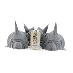 May include: Three gray 3D printed helmets with horns, arranged in a row, with a can of Japanese beer in the center.