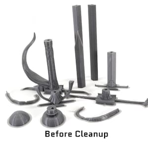 May include: A set of grey 3D printed parts for a model kit. The parts are in various shapes and sizes, including a curved piece, a tall column, and a base with a circular top. The parts are scattered on a white surface. Before Cleanup.