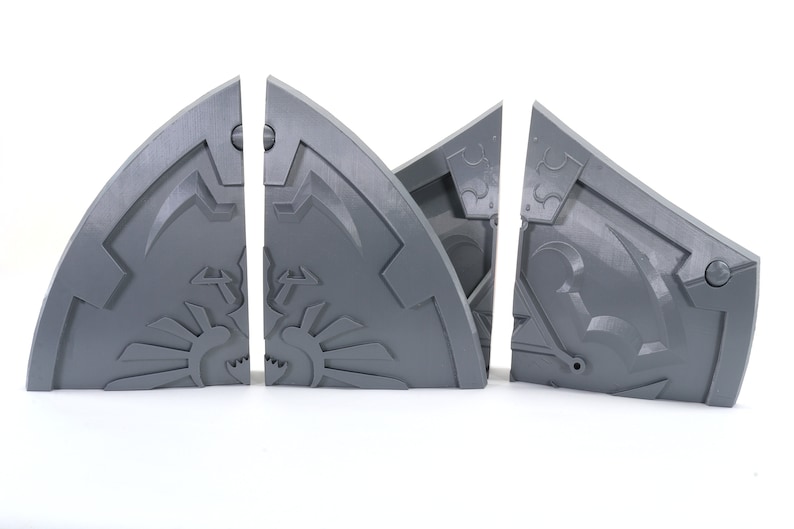 May include: Four gray plastic pieces of a puzzle that form a shield with a design on it.