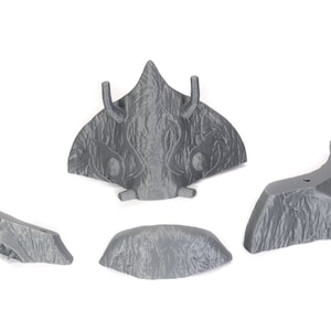 Puede incluir: Cinco piezas grises, texturizadas, impresas en 3D de un kit de maquetas. Las piezas tienen forma de nave espacial con una nariz puntiaguda y alas.