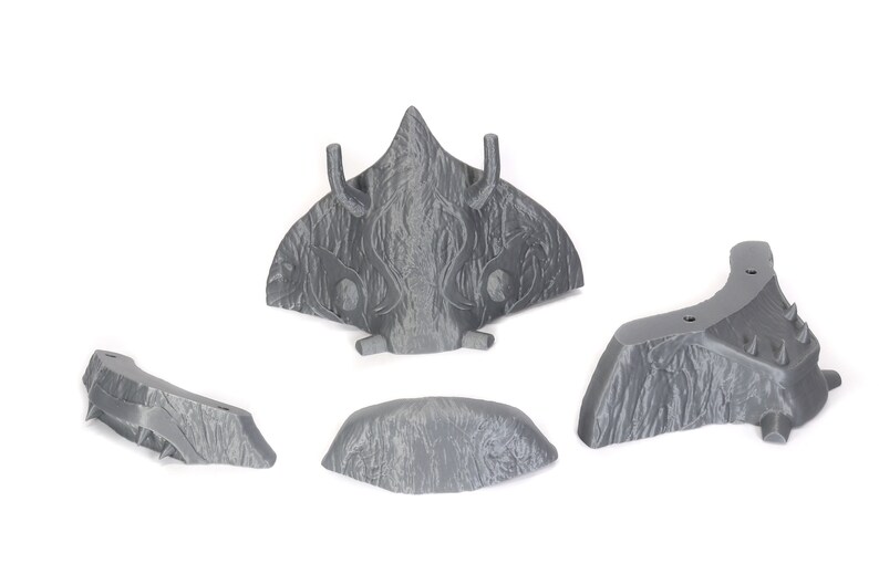 Puede incluir: Cinco piezas grises, texturizadas, impresas en 3D de un kit de maquetas. Las piezas tienen forma de nave espacial con una nariz puntiaguda y alas.