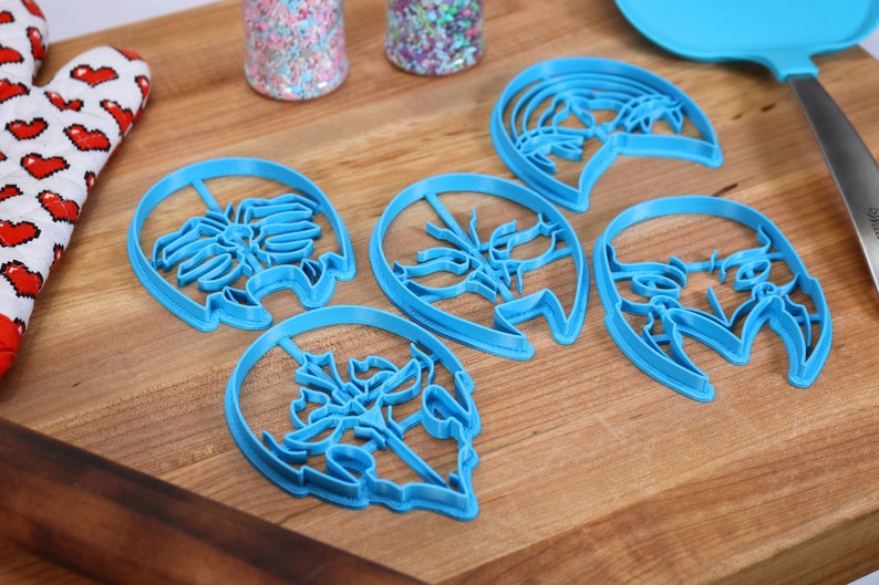 K&ouml;nnte beinhalten: F&uuml;nf blaue Plastik-Ausstecher in verschiedenen Formen. Die Ausstecher liegen auf einer Holzoberfl&auml;che.