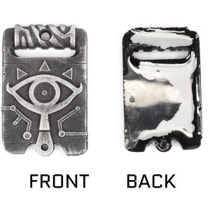 May include: A silver-toned metal charm featuring a stylised eye with a triangular design and a circuit board pattern. The back of the charm is plain and has a loop for attaching to a chain or bracelet.