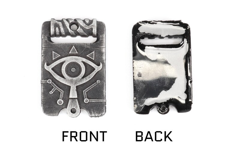 May include: A silver-toned metal charm featuring a stylised eye with a triangular design and a circuit board pattern. The back of the charm is plain and has a loop for attaching to a chain or bracelet.