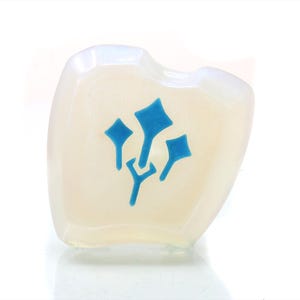 May include: A white, opaque, heart-shaped glass paperweight with a blue, stylized design of three stylized flowers.