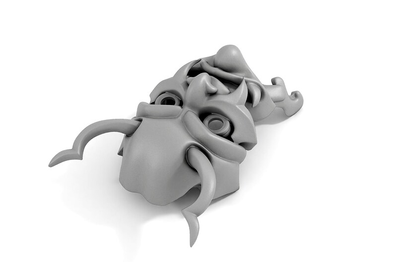 May include: A pair of gray, stylized, ceramic masks with horns and exaggerated features. The masks are stacked on top of each other.