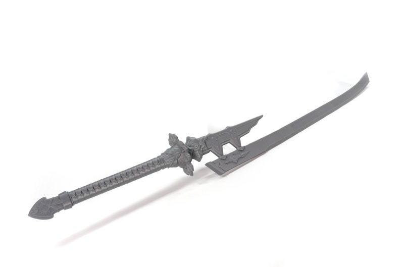 May include: A grey, decorative sword with a detailed handle and a sharp blade. The sword has a unique design with intricate carvings and a pointed tip.