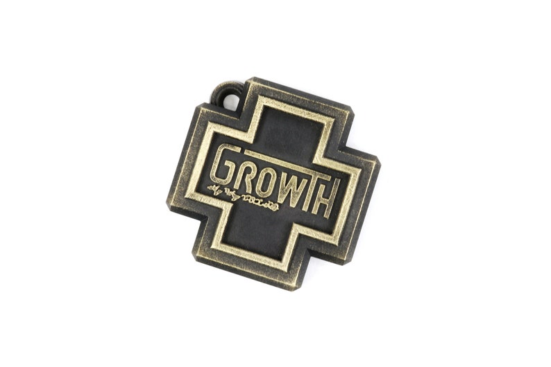 May include: A black metal charm in the shape of a cross with a gold border. The word "GROWTH" is written in gold lettering inside the cross.