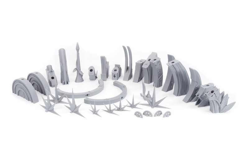 May include: A collection of gray, 3D-printed terrain pieces for tabletop gaming. Includes various structures, arches, spires, and plant-like elements. The pieces are designed to create a detailed and immersive environment for miniature games.