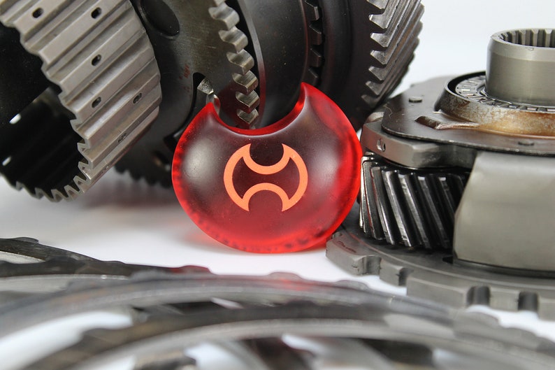 May include: A red, crescent-shaped object with a stylized orange symbol in the center. The object is surrounded by several metal gears.