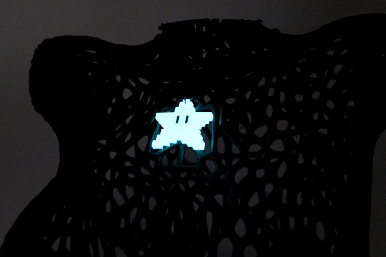 May include: A white star-shaped object with a face on it, glowing against a black background.