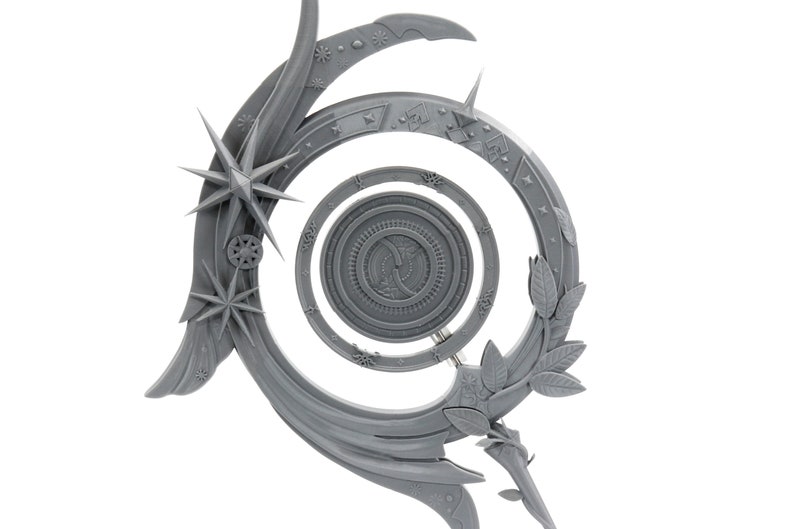 May include: A gray, decorative celestial-themed object with a spiral design. It features star and leaf accents, with a central circular element. The object has a detailed, textured surface and is set against a white background.