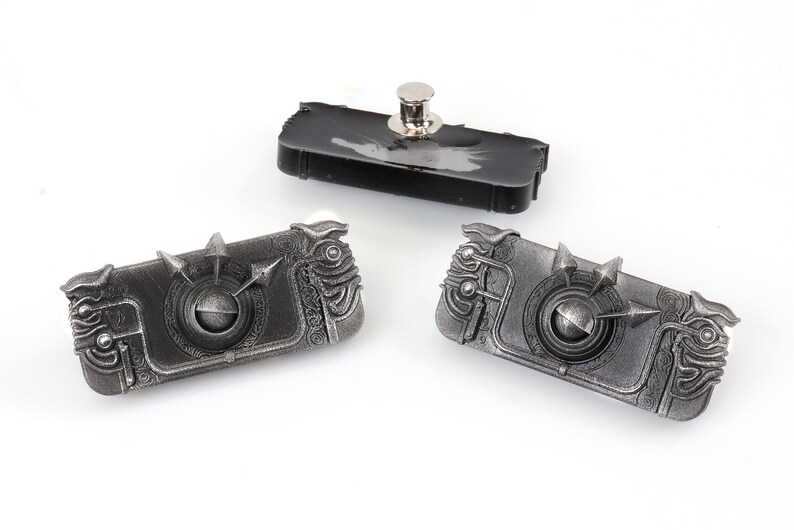 May include: Three silver-coloured metal keychains with intricate designs. Each keychain features a circular centre with a spinning element and a textured, detailed outer edge.