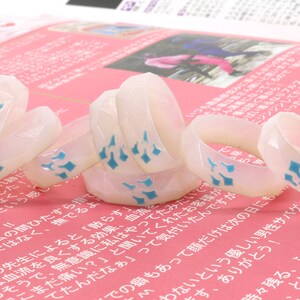 May include: A group of white rings with blue diamond patterns stacked on top of each other. The rings are made of a translucent material and have a glossy finish.