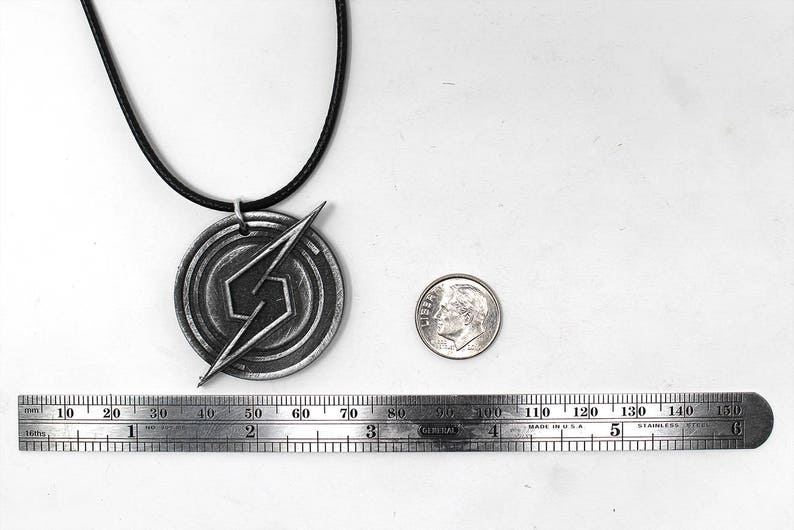May include: A silver necklace with a pendant featuring a stylized lightning bolt design. The pendant is about 2 inches in diameter and is on a black cord.