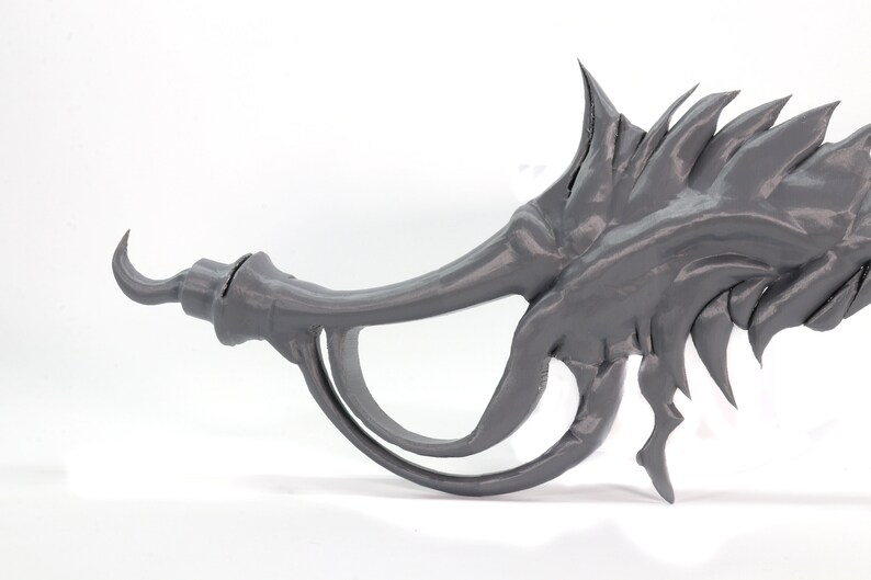 May include: A gray 3D printed dragon claw prop with a sharp, curved point and a textured, spiky surface.