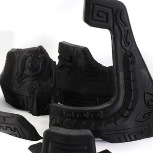以下が含まれることがあります： 複雑なデザインが施された黒い3Dプリントプラスチック製の部品のセット。部品は白い表面に配置されています。