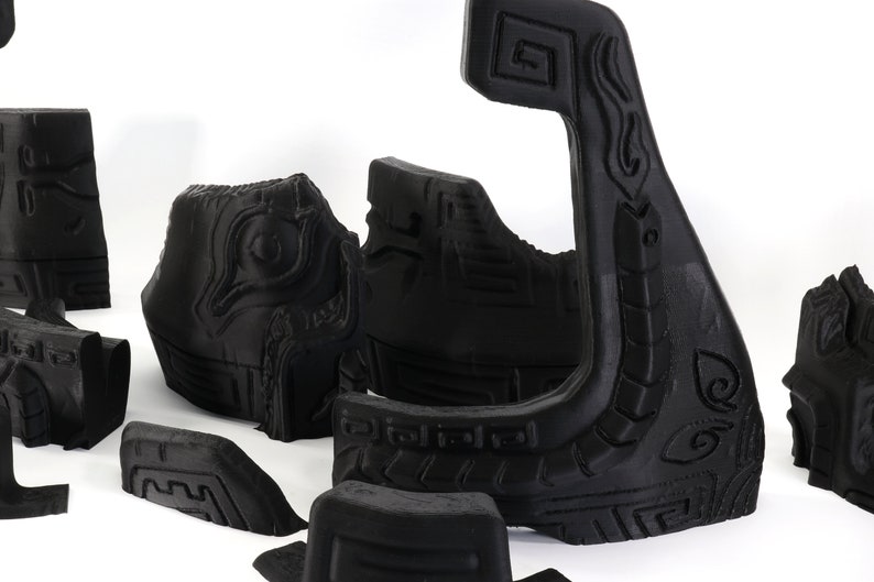 以下が含まれることがあります： 複雑なデザインが施された黒い3Dプリントプラスチック製の部品のセット。部品は白い表面に配置されています。