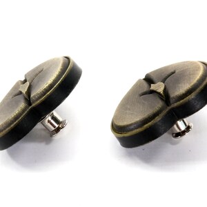 May include: Two antique gold-toned heart-shaped buttons with black trim and a metal shank.