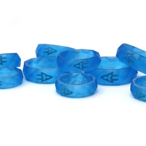 May include: A group of eight blue silicone rings with a geometric design and a small symbol on each ring.
