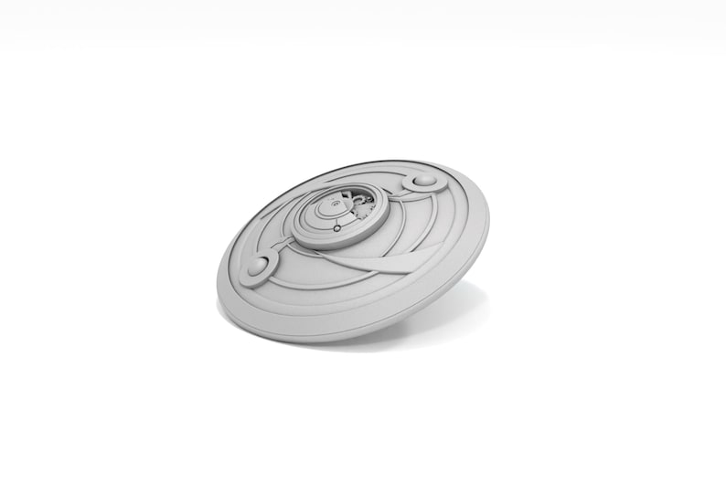 May include: A light gray, circular object with a detailed, layered design. The object has a central, raised circular element with intricate detailing, surrounded by concentric rings and curved accents. The overall aesthetic is futuristic.