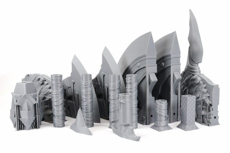 Puede incluir: Un conjunto de piezas de pl&aacute;stico gris impresas en 3D para un kit de maquetas. Las piezas son de diversas formas y tama&ntilde;os, incluyendo una cabeza de hacha grande, una cabeza de hacha m&aacute;s peque&ntilde;a y varias piezas cil&iacute;ndricas.