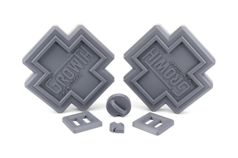 May include: A set of gray plastic building blocks with the word "GROWTH" embossed on two of the blocks. The blocks are shaped like a cross and have a variety of other shapes, including a circle, a square, and a rectangle.