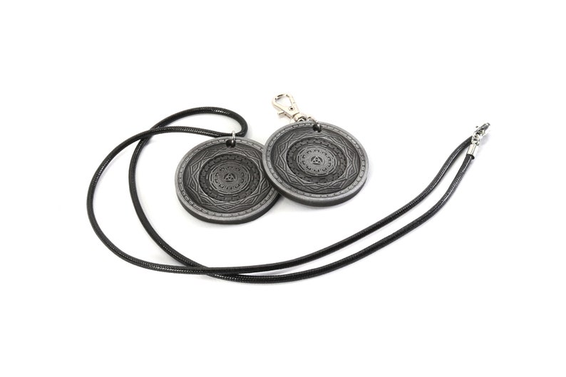 May include: A black leather necklace with two silver pendants featuring intricate circular designs. The pendants have a raised, textured pattern.