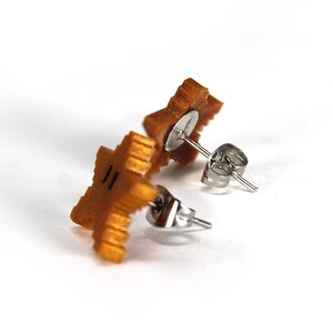 May include: A pair of gold star-shaped earrings with silver posts and backs.