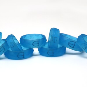 May include: A group of seven blue silicone rings with a raised logo on each ring.