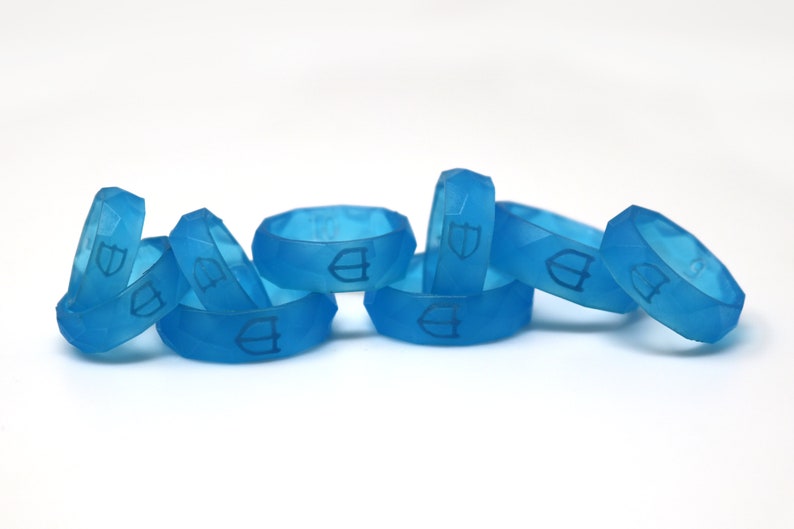 May include: A group of seven blue silicone rings with a raised logo on each ring.