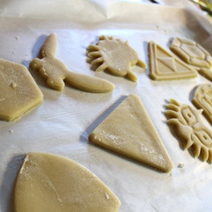 Puede incluir: Una hoja de papel para hornear con varias formas de masa para galletas sin hornear, incluyendo un tri&aacute;ngulo, un c&iacute;rculo, una estrella y algunas otras formas abstractas.