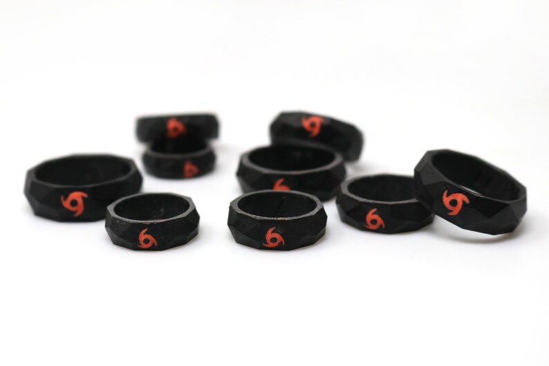 May include: A set of eight black silicone rings with a red swirl design. The rings are textured and have a geometric shape.
