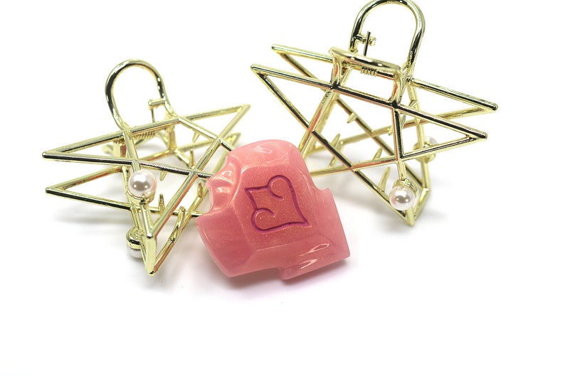May include: Two gold-colored star-shaped hair clips with a pearl accent and a pink hair clip with a heart design. The hair accessories are on a white background.
