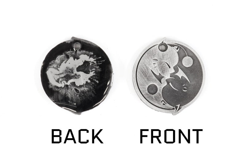 May include: A silver-colored metal charm with a yin yang design on one side and a blank surface on the other side.