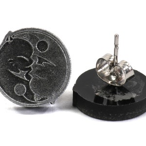 May include: A pair of silver stud earrings with a black and white yin yang symbol design. The earrings have a silver post and butterfly backing.