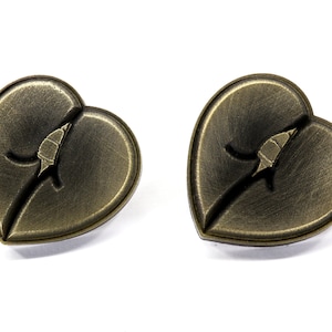 May include: A pair of heart-shaped earrings with a bronze finish. Each earring features a stylized leaf design with a crack running through it.