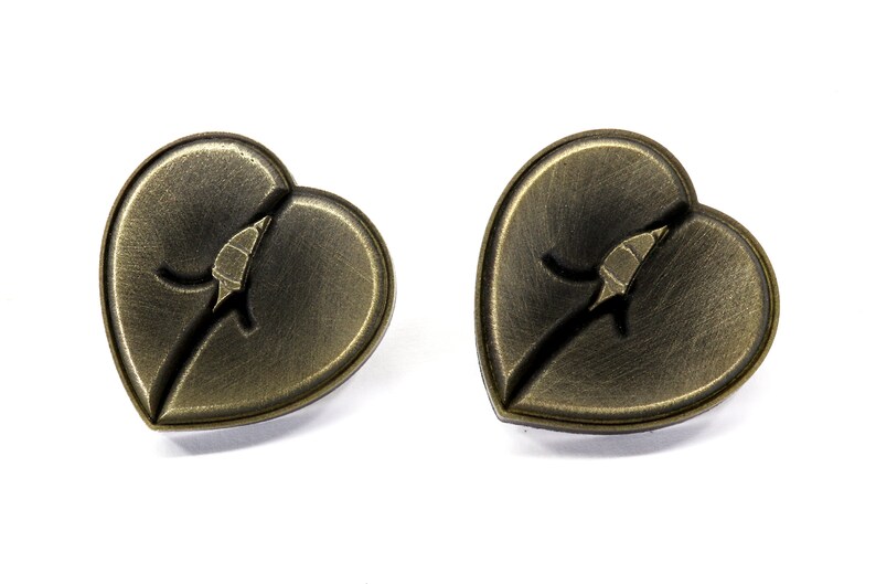 May include: A pair of heart-shaped earrings with a bronze finish. Each earring features a stylized leaf design with a crack running through it.
