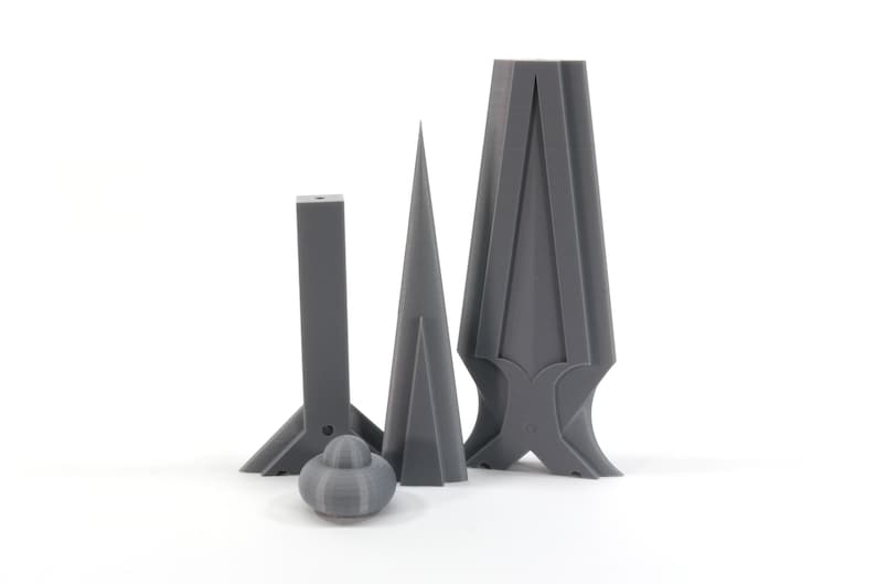 May include: Three gray 3D printed objects, two are tall and narrow, one is short and wide, with a round gray object in the front.