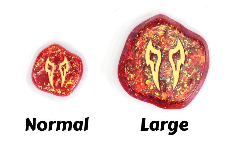May include: Two resin cabochons with a gold glitter finish and a gold flame design. The cabochon on the left is labeled "Normal" and the cabochon on the right is labeled "Large".
