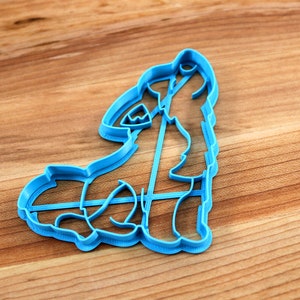 May include: A blue plastic cookie cutter shaped like a wolf howling at the moon.