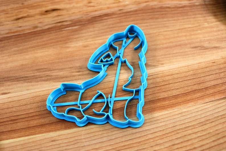 May include: A blue plastic cookie cutter shaped like a wolf howling at the moon.